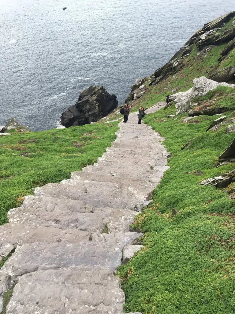 Visitors climbing the stone steps on Skellig Michael with the landscape visible behind